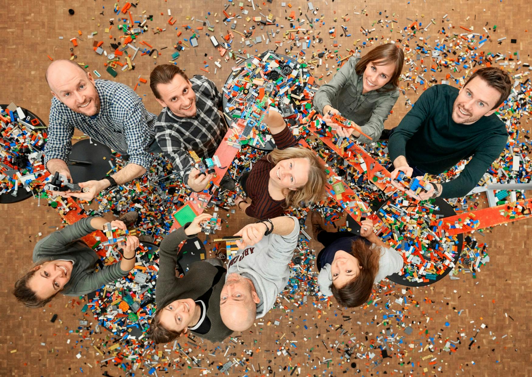 Foto oppefra af ni glade medarbejdere med konfetti, som fejrer den positive udvikling af deres samarbejde 