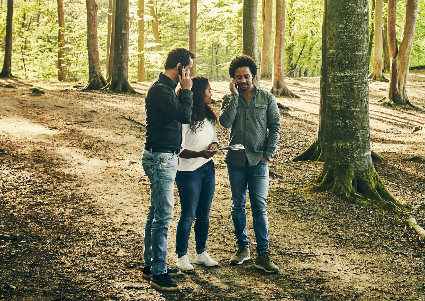 Tre mennesker i en skov i gang med teambuildingaktiviteten GPS Adventure som kan afvikles på Fyn