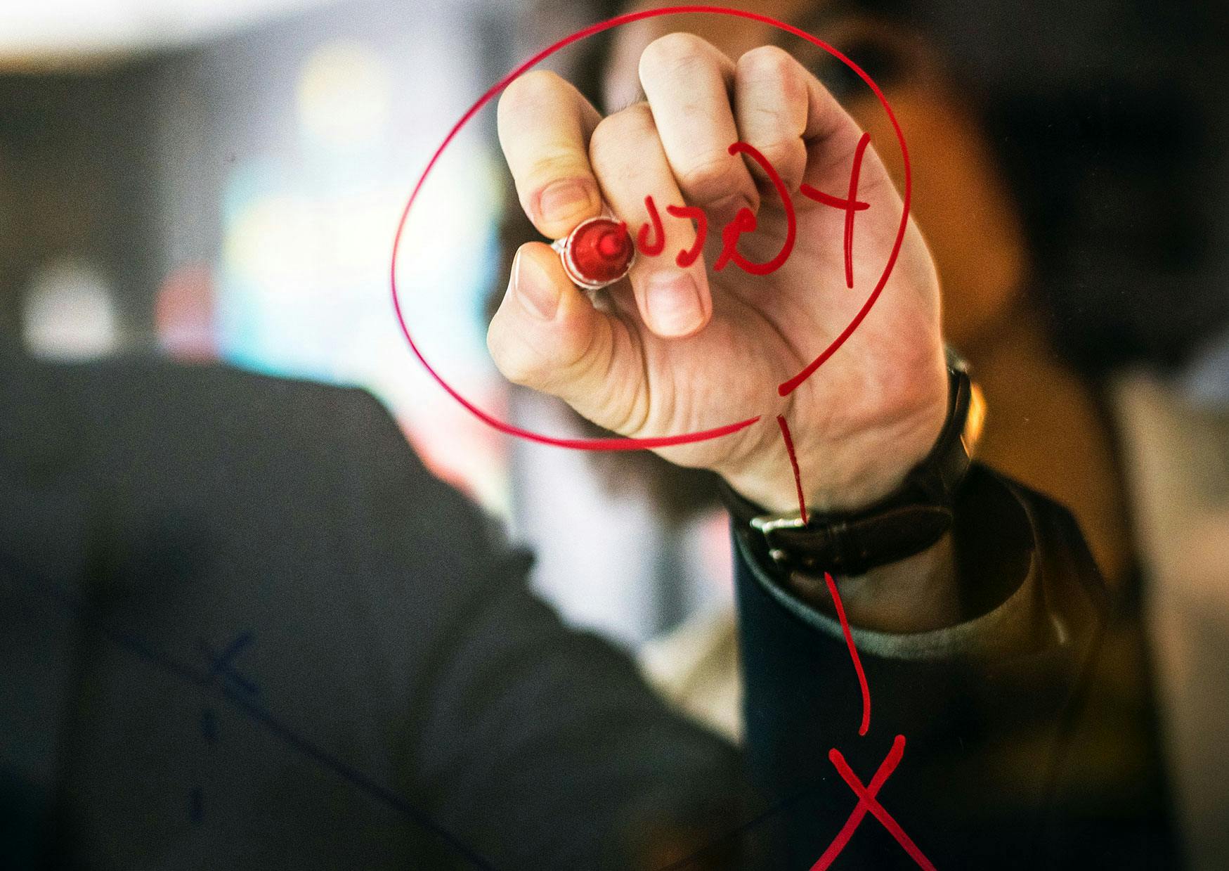 Hånd der skriver med en rød tusch under planlægning af HR årshjul